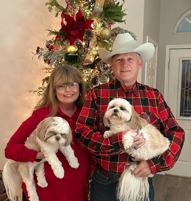 Happy couple with two dogs posing in front of a Christmas tree