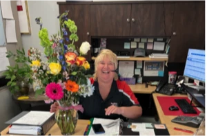 Woman smiling at office desk with flowers